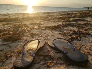 High angle view of shoes on beach against sky during sunset