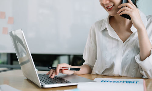 Midsection of businesswoman using laptop at office