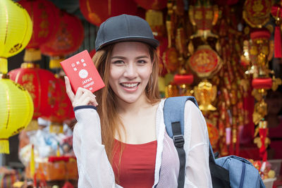 Portrait of beautiful woman holding japanese passport against traditional lanterns in city