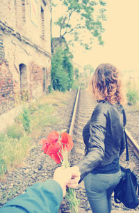 Rear view of girl holding flowers on tree