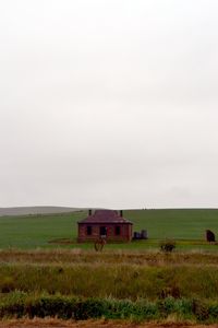 Empty bench on field against clear sky