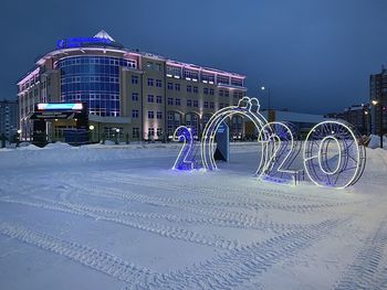 Illuminated ferris wheel in city during winter