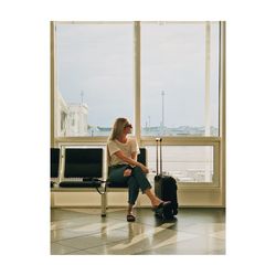 Full length of woman sitting on floor against window