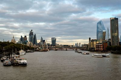 View of buildings by river against cloudy sky