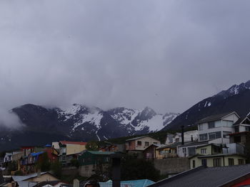 Houses and snowcapped mountains against sky