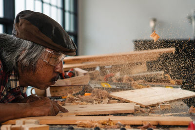 Carpenter blowing sawdust on wood at work