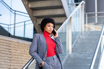 A young african-american businesswoman wearing a red turtleneck and a suit in a business building