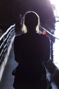 Rear view of silhouette woman walking on footbridge