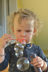 Close-up of girl blowing bubbles at home