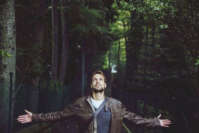 Young man with arms outstretched in the forest