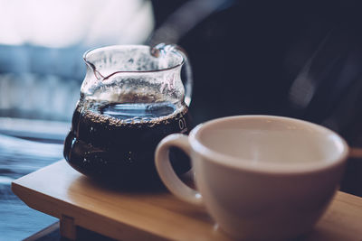 Close-up of black coffee in jug by cup on table