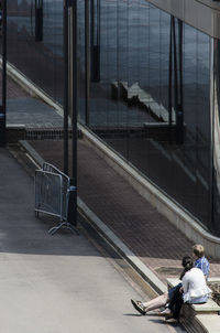 Side view of two people sitting by the road