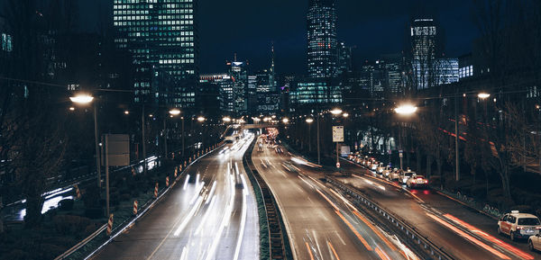 Light trails on road amidst buildings in city at night