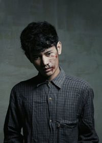 Thoughtful injured young man standing against wall