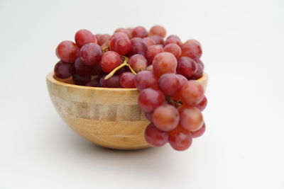 High angle view of grapes in bowl against white background