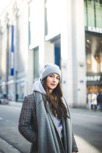 Portrait of smiling young woman standing in city during winter