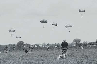 Hot air balloons flying over field against sky