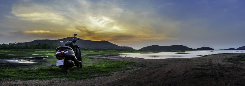 Dramatic sky at lake and hill landscape with motorbike foreground