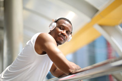 Portrait of young man standing against railing