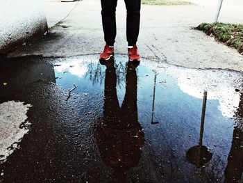 Low section of person standing on wet street