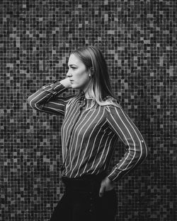 Side view of a young woman standing against wall