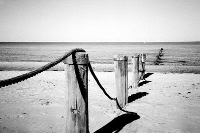 Wooden posts on beach against clear sky