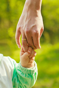 Close-up of baby holding mothers finger outdoors