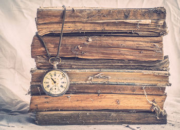 Close-up of pocket watch on old stacked books