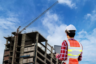 Rear view of man at construction site against sky