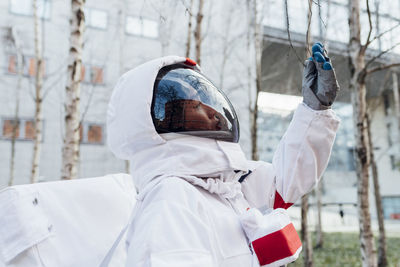 Female astronaut examining tree twig in garden