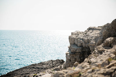 Rock formations by sea against clear sky