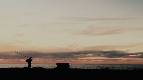 Silhouette of people on beach at sunset