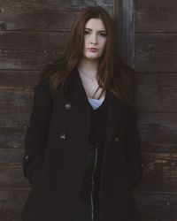 Portrait of a beautiful young woman standing against wall