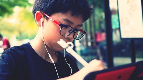 Close-up of boy wearing headphones while drawing