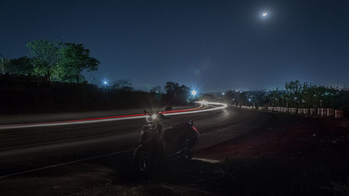 Light trails on road against sky at night