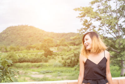 Beautiful young woman looking away against sky