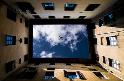Directly below view of airplane flying over building against sky