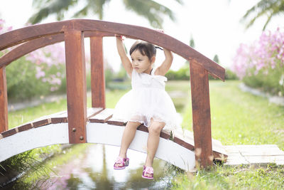 Side view of young woman sitting on railing