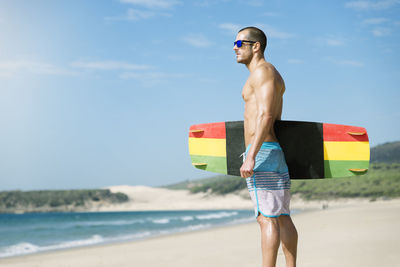 Full length of shirtless man standing on beach