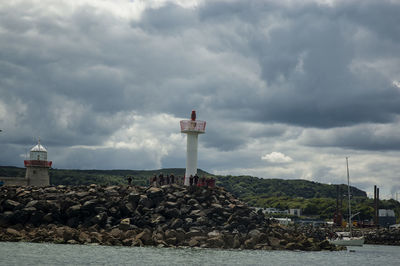 Lighthouse by sea against sky