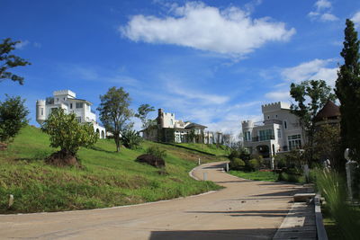 Road amidst buildings against blue sky