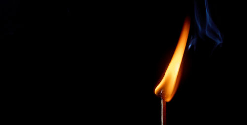 Close-up of lit candle against black background