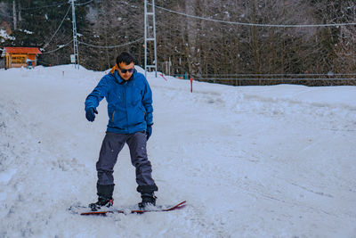 Full length of man snowboarding on snow covered land