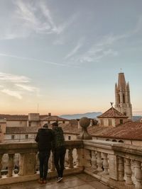 Rear view of people standing by buildings against sky