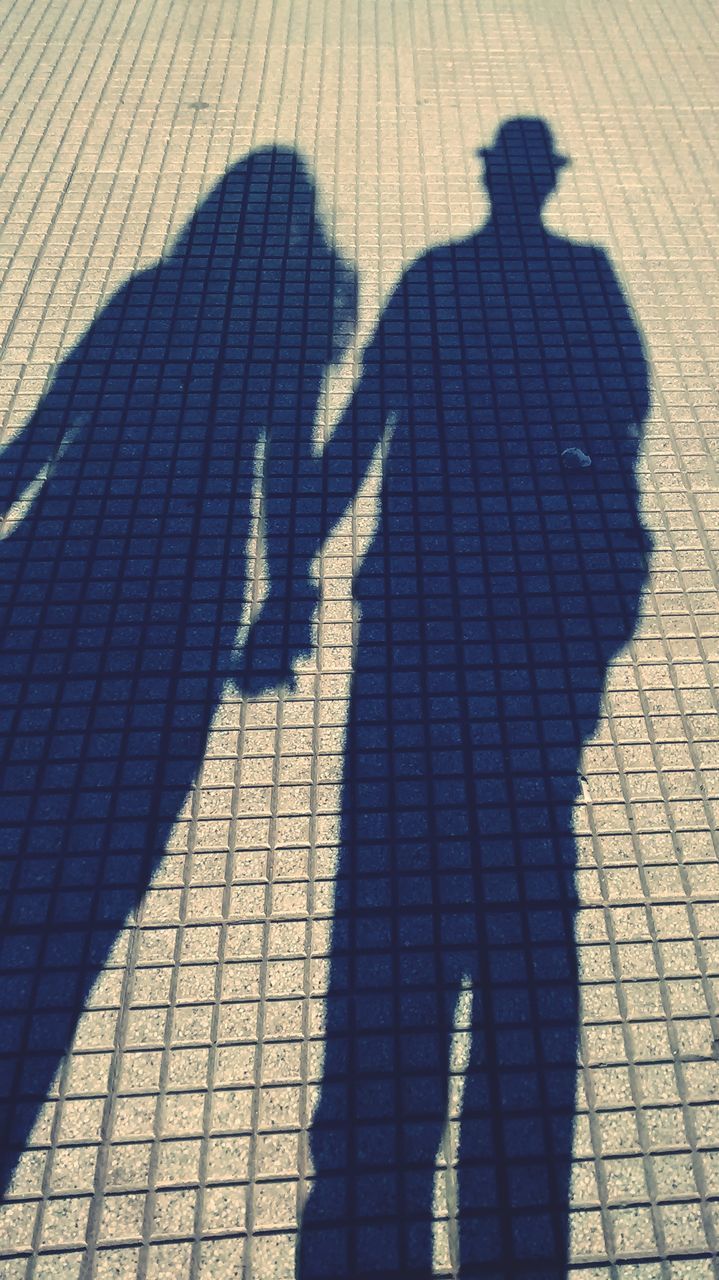 shadow, two people, real people, high angle view, men, togetherness, love, sunlight, bonding, nature, day, lifestyles, focus on shadow, positive emotion, people, adult, women, emotion, couple - relationship, leisure activity, outdoors, long shadow - shadow, paving stone