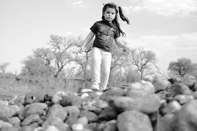 Portrait of young woman standing on rock against sky