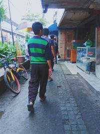 Rear view of people walking on road in city