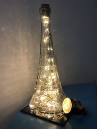 Close-up of illuminated lamp on table against wall