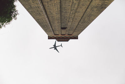 Directly below shot of airplane over building against clear sky