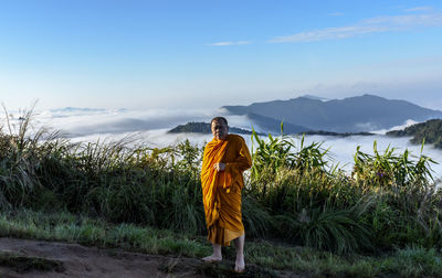 Portrait of monk standing on mountain against sky